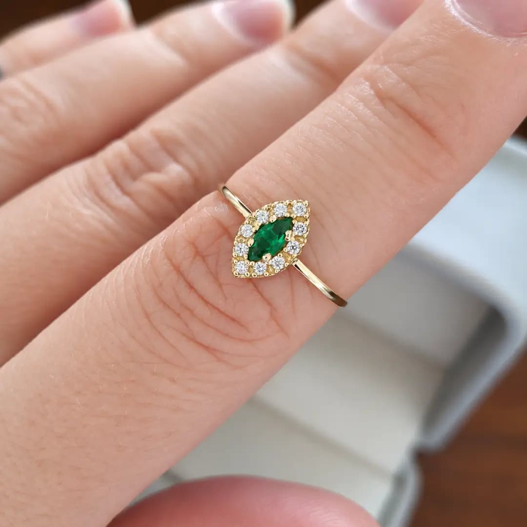 Anel Liz em ouro amarelo com esmeralda verde usado no dedo