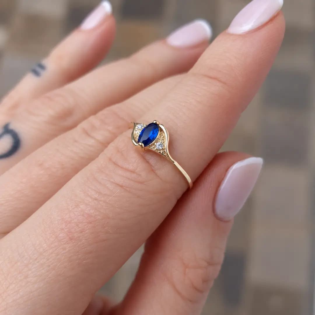 Anel Luana em ouro amarelo com pedra azul usado no dedo
