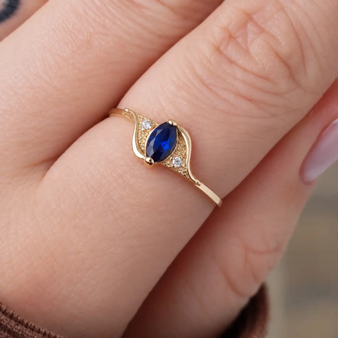 Detalhe do Anel Luana com pedra azul central em ouro amarelo